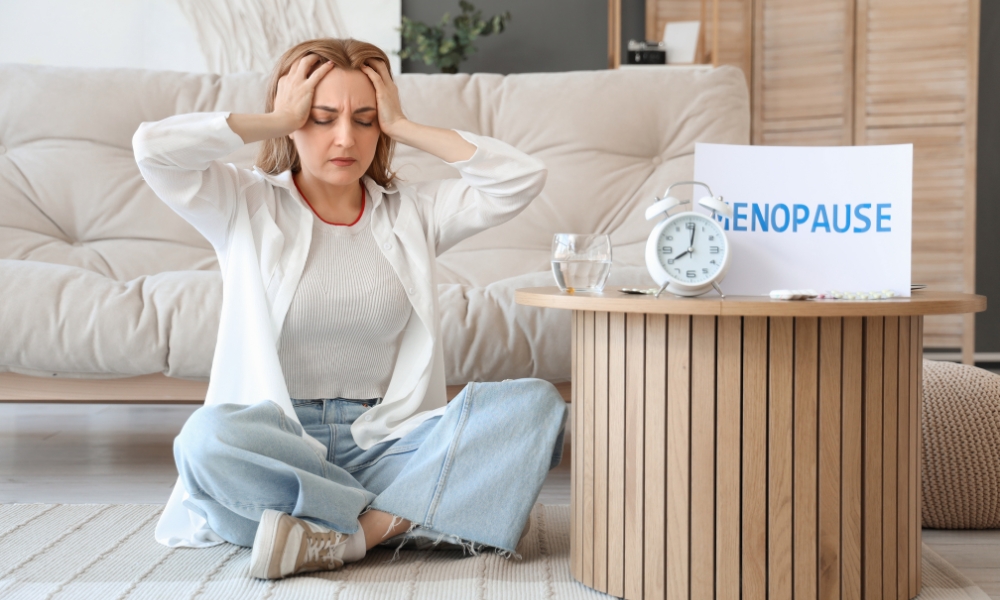 Woman experiencing symptoms following surgical menopause including hot flashes and night sweats while sitting on her bed